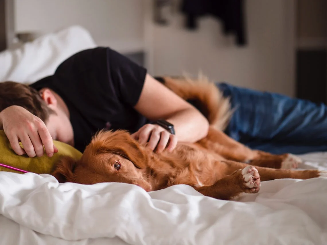 a teenager cuddling a dog in bed