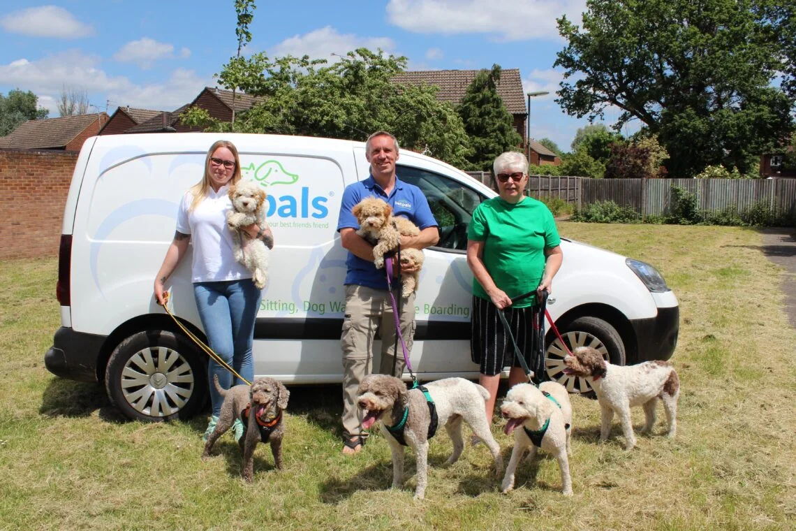 two women and a man in front of a Petpals van with dogs